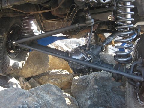 1985 Ford Bronco - Close-up of off-road vehicle suspension and drivetrain components on rocks.