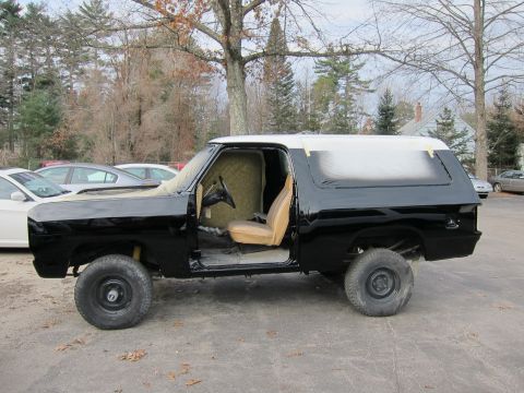 1987 Dodge 1500 - Side view of a black SUV undergoing bodywork, with the roof and rear section taped off for painting.