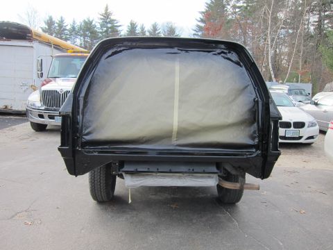 1987 Dodge 1500 - Pickup truck bed covered for paint work, with other vehicles and a truck in the background.