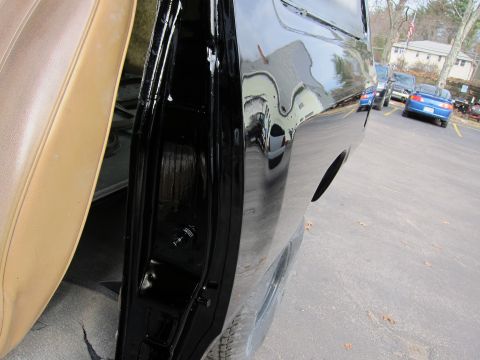 1987 Dodge 1500 - A close-up shot of a black pickup truck's side door, revealing both the interior and exterior panels, with other vehicles visible in the ba…