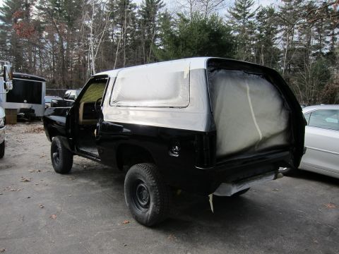 1987 Dodge 1500 - This black SUV with a white roof is seen in a three-quarter rear view, appearing to be in the process of being painted.
