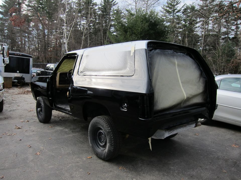 Black SUV with white roof, rear quarter view, undergoing paintwork