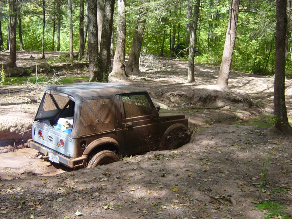 Muddy off-road vehicle stuck in a ditch in the woods