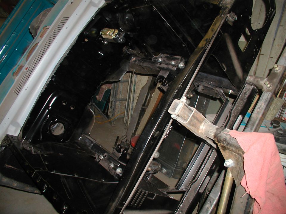 Black-painted bare engine bay and firewall of a Ranchero body mounted on a rotisserie in a garage