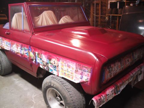 1968 Ford Bronco - A red 1968 Ford Bronco is being prepped for painting, with custom graphics applied to the fenders and newspaper protecting the grille.