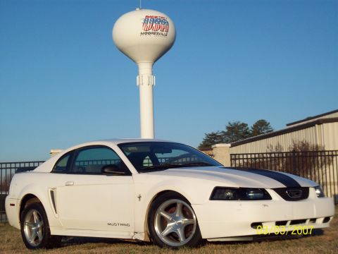 2000 Ford Mustang - A white coupe with black racing stripes is parked in front of a water tower.