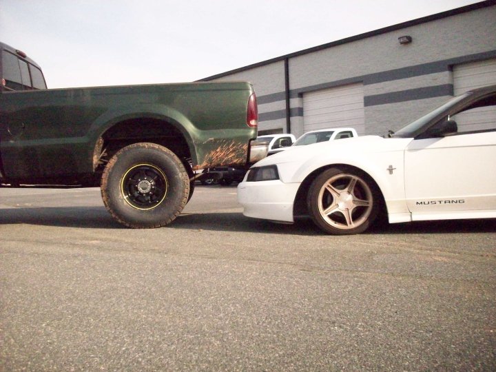 White 2000 Ford Mustang parked close to a green Ford pickup truck