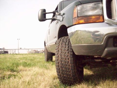2000 Ford F-350 - A close-up view of the front tire and fender of a dark green 2000 Ford F-350 pickup truck.