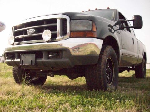 2000 Ford F-350 - This 2000 Ford F-350 is captured in a low-angle front 3/4 view, highlighting its chrome grille and extended tow mirrors.