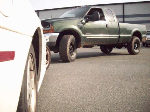2000 Ford F-350 - A green Ford F-350 pickup truck is parked next to a white car.