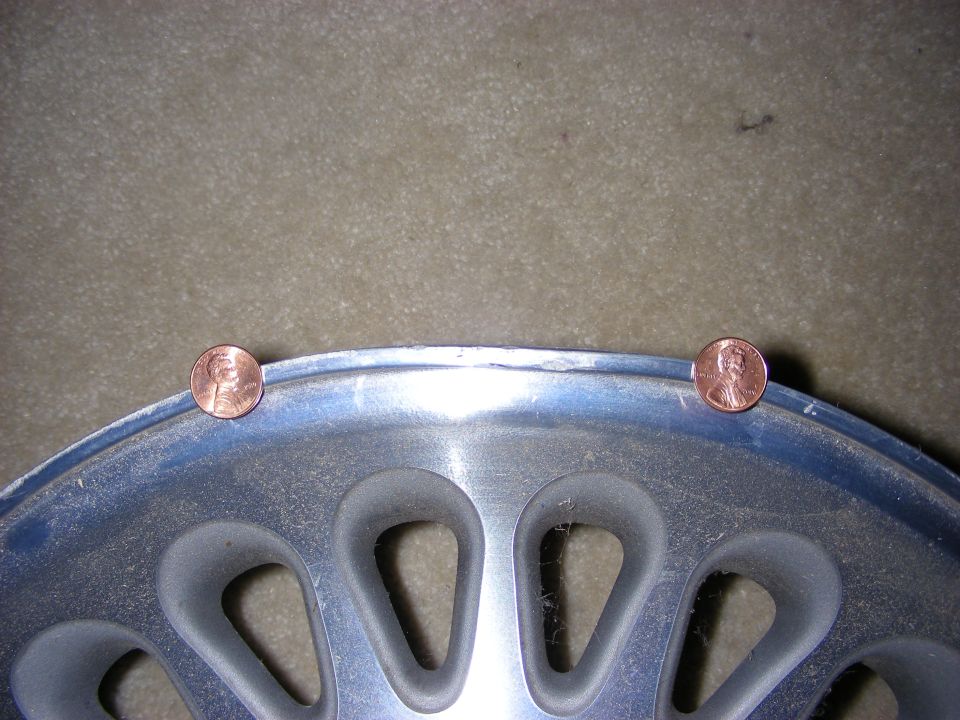 Silver wheel rim with two pennies placed on its edge