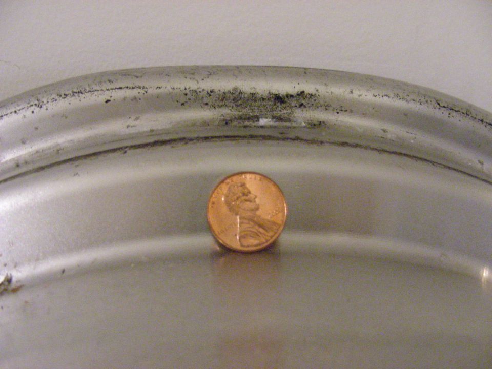 Close-up of a silver wheel rim with a penny placed on it