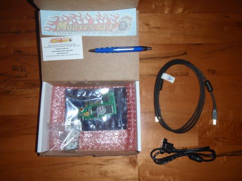 1996 Ford Bronco - Contents of a Moates.Net tuning solutions box, including a circuit board and cables, are laid out on a wooden surface.