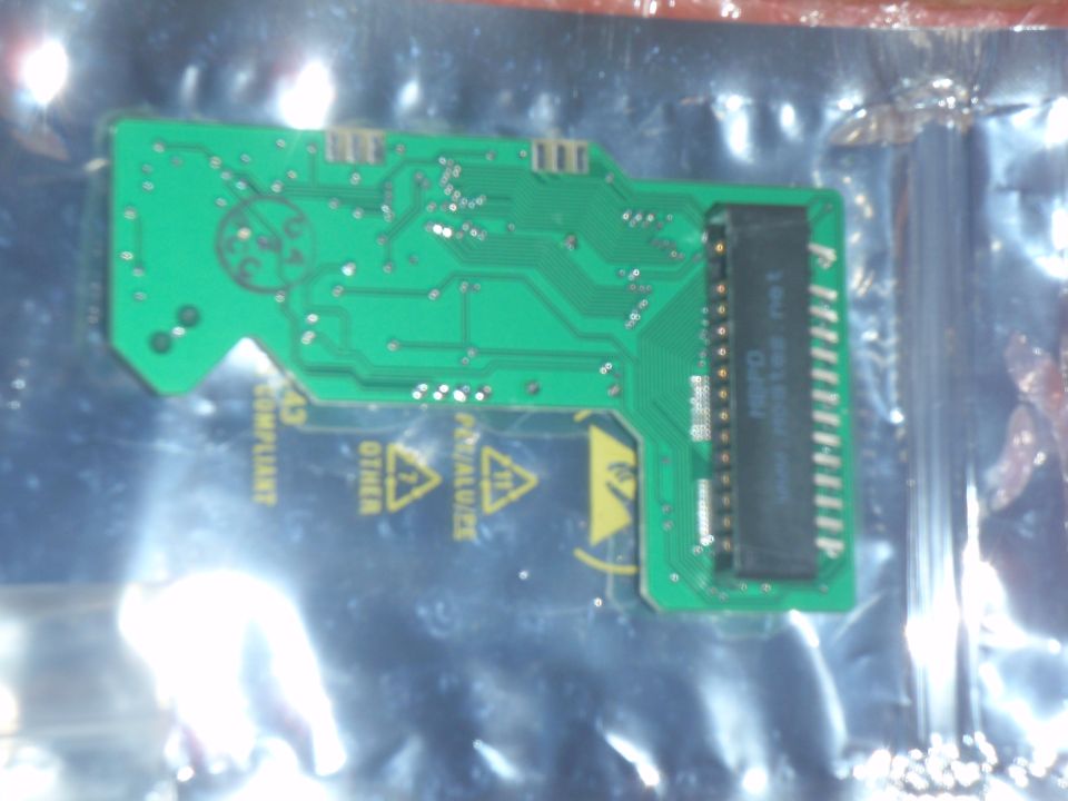 Green circuit board with black connector and warning symbols