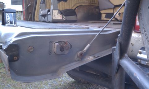 1979 Ford Bronco - Detail of the tailgate latch mechanism and support cable, with a 4XRAC device visible.