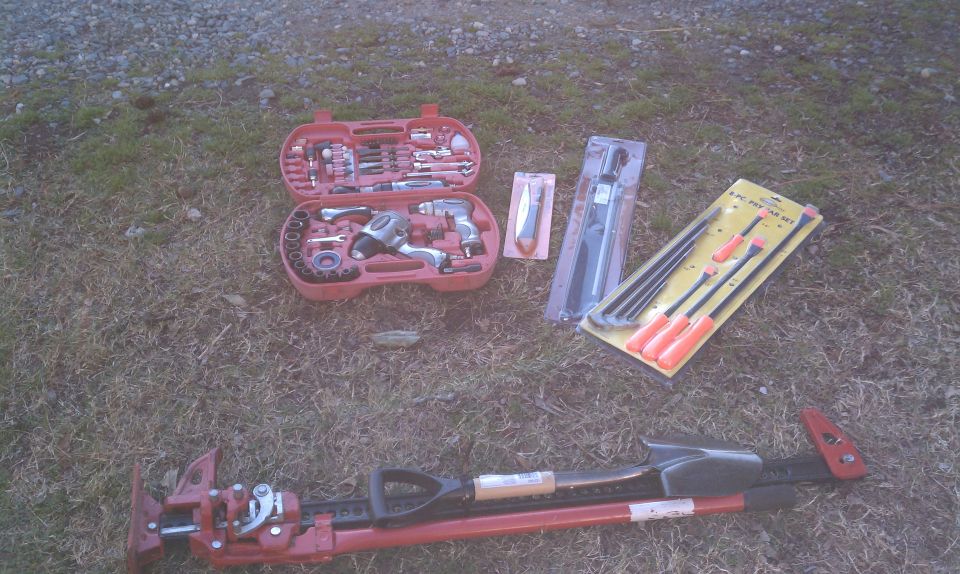 Toolbox with sockets and impact wrench, pry bar set, and a hi-lift jack with shovel attachment on grass