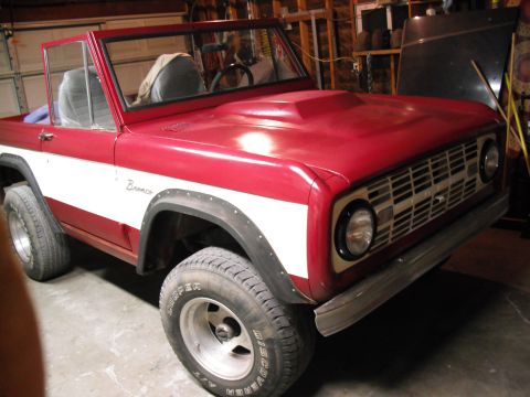 1968 Ford Bronco - This classic Ford Bronco is shown in a garage, a two-tone red and white paint scheme and a prominent hood scoop.