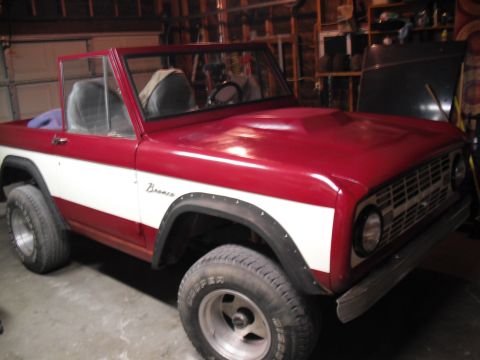 1968 Ford Bronco - Red and white 1968 Ford Bronco with aftermarket hood scoop, parked indoors.
