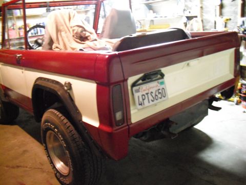 1968 Ford Bronco - The rear of a red and white 1968 Ford Bronco is visible, with a California license plate mounted on the tailgate.