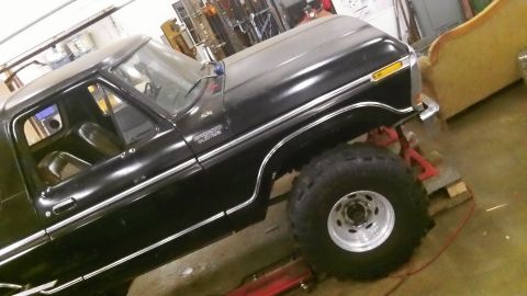1979 Ford Bronco - This black pickup truck features large off-road tires and appears to be undergoing modifications.