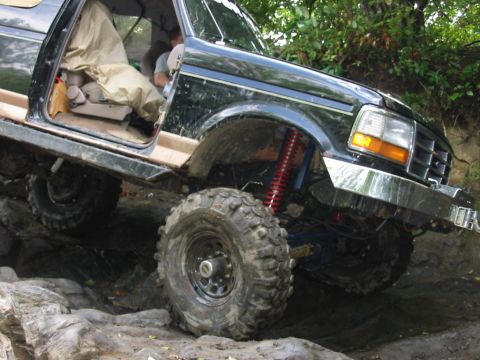 1994 Ford Bronco - This modified SUV is shown tackling a challenging off-road course with large tires and suspension upgrades.