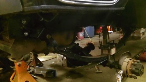 1979 Ford Bronco - Close-up view of the rear suspension and frame of a vehicle undergoing maintenance or modification.
