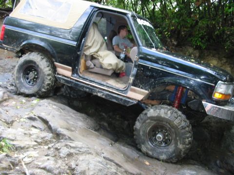 1994 Ford Bronco - A dark green 1992 Ford Bronco navigates a rocky trail with its doors removed.