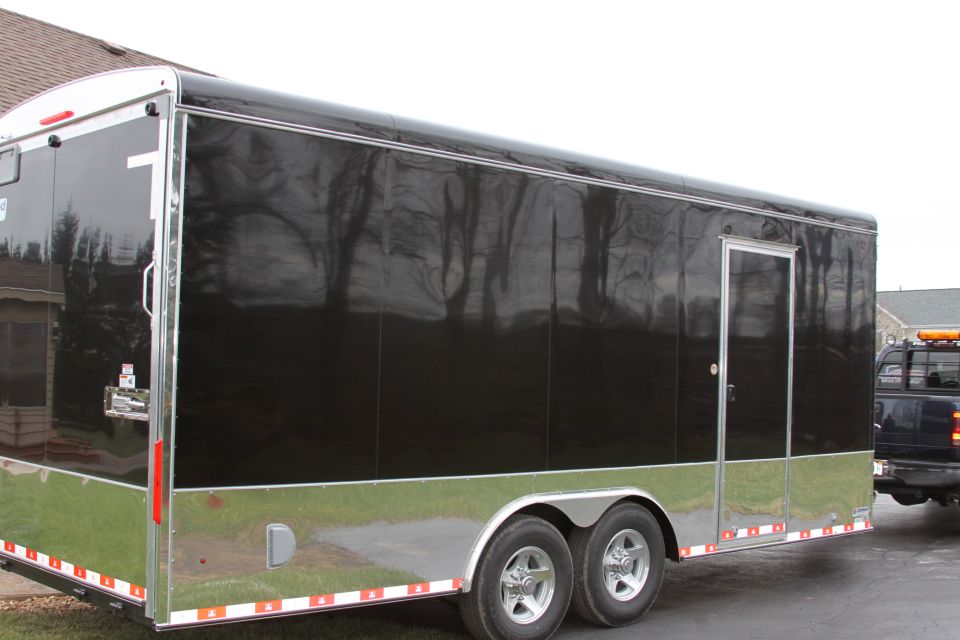 Black enclosed trailer with chrome trim, towed by a dark pickup truck