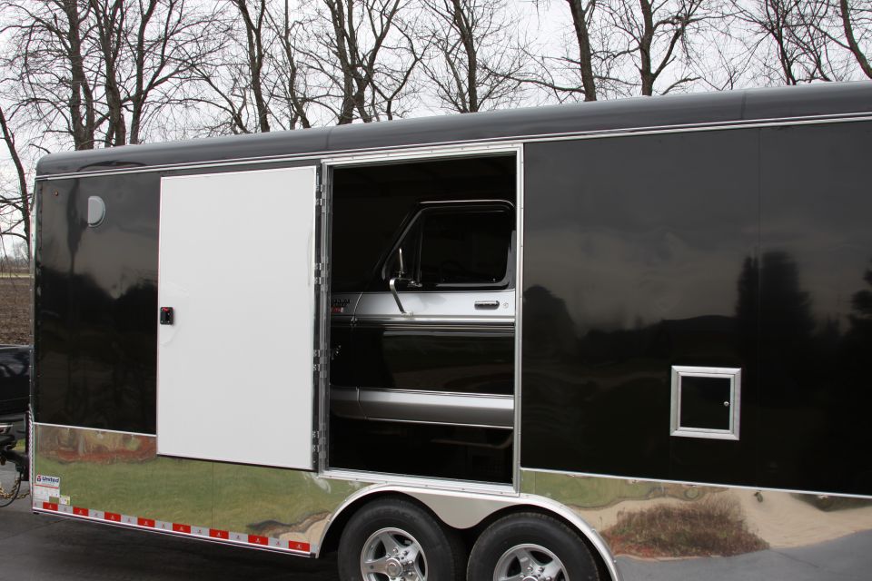Trailer with open side door revealing a vintage pickup truck interior, silver and black