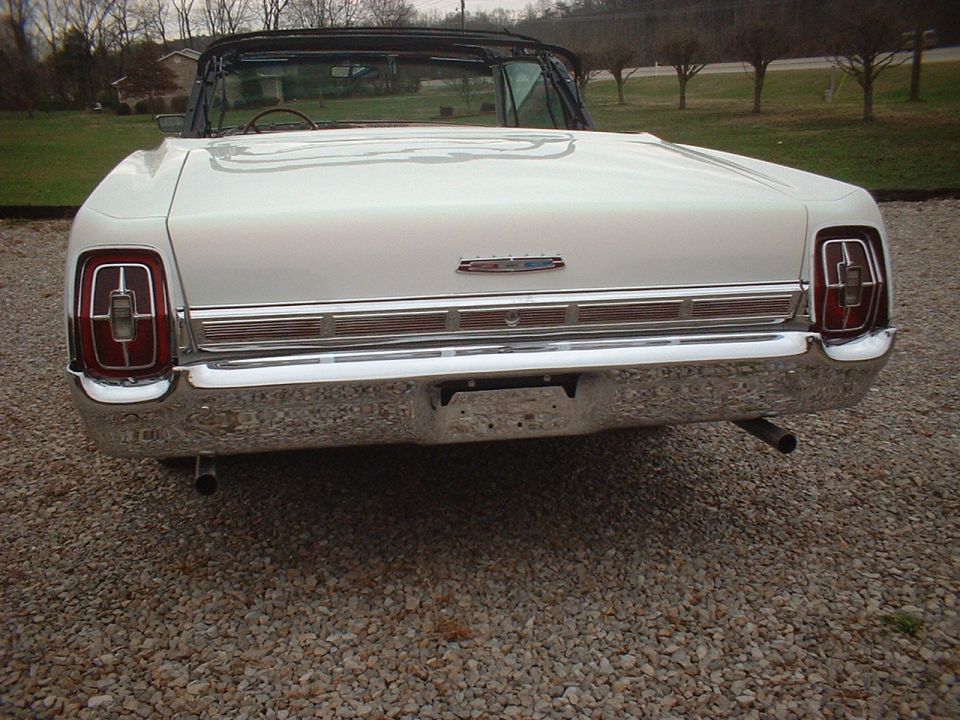 White 1967 Ford Galaxie convertible rear view, chrome bumper, dual exhaust pipes, gravel lot