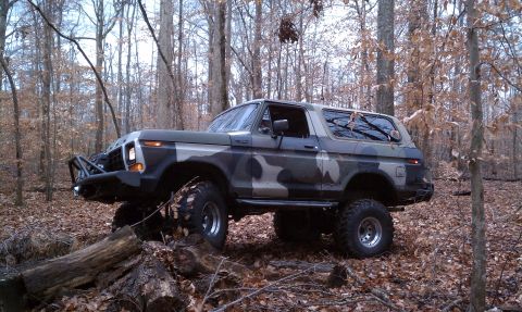 1979 Ford Bronco - Modified 1978 Ford Bronco navigates a rough, wooded terrain with fallen logs.