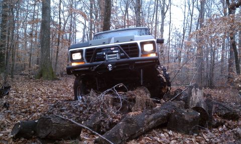 1979 Ford Bronco - This modified Ford Bronco navigates a challenging path through a wooded area with fallen logs.
