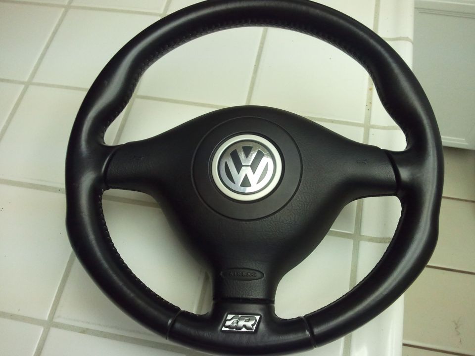 Black Volkswagen steering wheel with silver emblem and 'R' logo