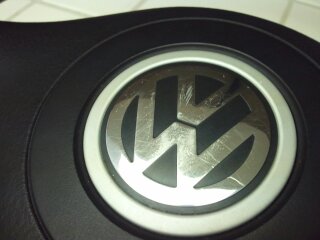 1989 Ford Bronco - Volkswagen emblem on a steering wheel, showing visible scratches on the chrome.