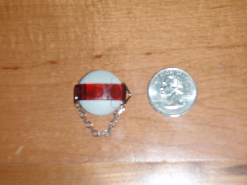 White reflector with red band and chain next to a US quarter