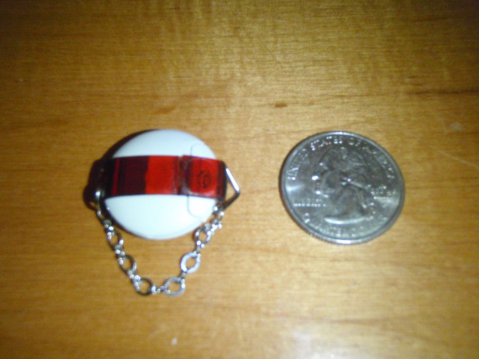 White keychain fob with red stripe and chain next to a quarter