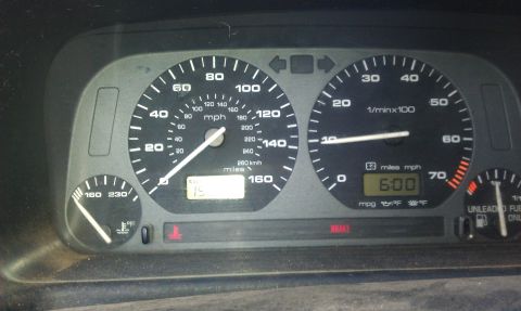 1991 Ford Festiva - Interior view of a vehicle's dashboard, displaying the speedometer, tachometer, and a digital clock showing 6:00.