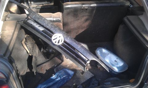 1991 Ford Festiva - The trunk of a car holds a Volkswagen grille and a spare headlight.