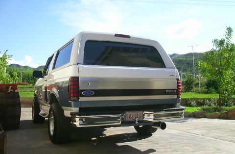 1993 Ford Bronco - Rear view of a two-tone Ford Bronco parked outdoors on a sunny day.