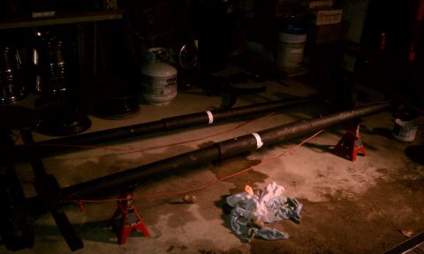 1990 Ford Bronco - Two large pipes are elevated on jack stands in a garage setting, with various items visible in the background.