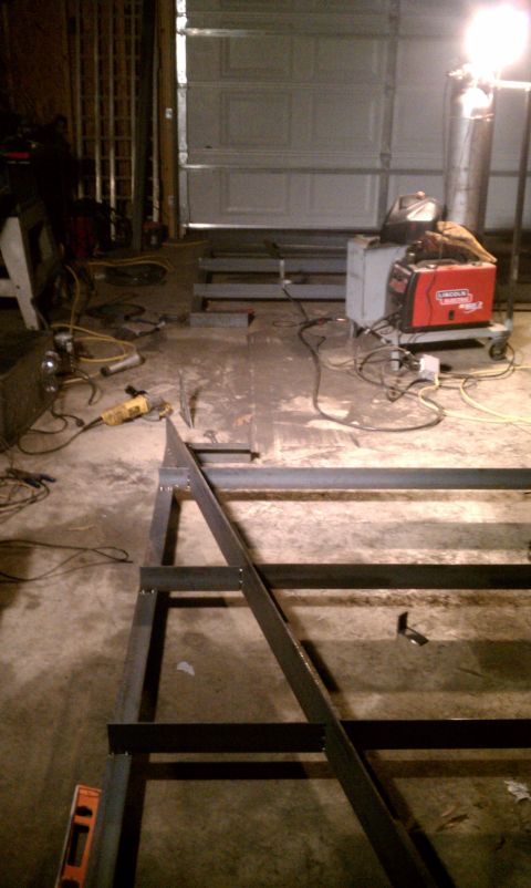 1990 Ford Bronco - A metal frame is being constructed in a garage, with welding equipment and tools visible.