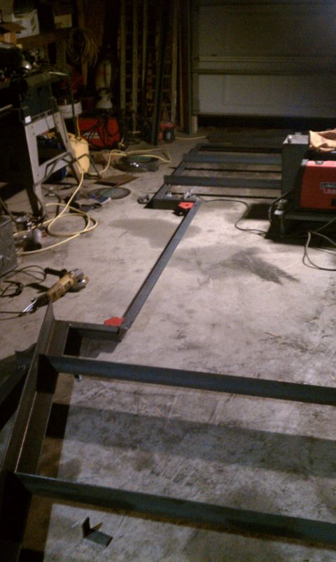 1990 Ford Bronco - Metal frame construction in progress on a garage floor, with tools and equipment visible.