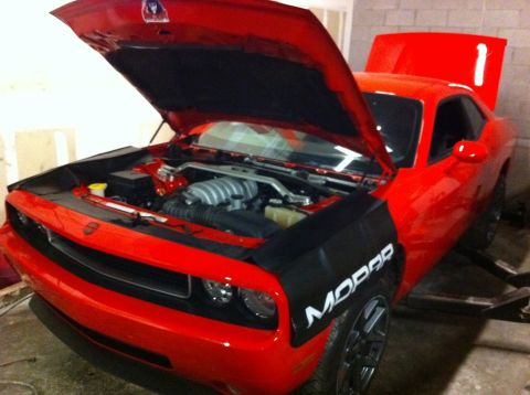 2010 Dodge Challenger - A red Dodge Challenger is shown with its hood and trunk open, revealing the engine bay and a Mopar logo on fender covers.