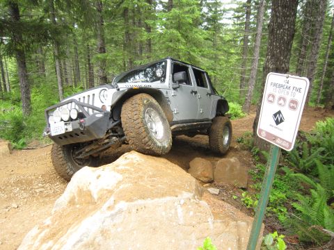 2008 Jeep Wrangler - A silver Jeep Wrangler navigates a challenging off-road course with steep inclines and large rocks.