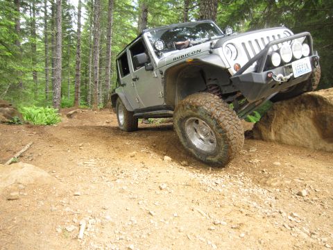 2008 Jeep Wrangler - A silver 2008 Jeep Wrangler Rubicon navigates a rocky obstacle on a forest trail.