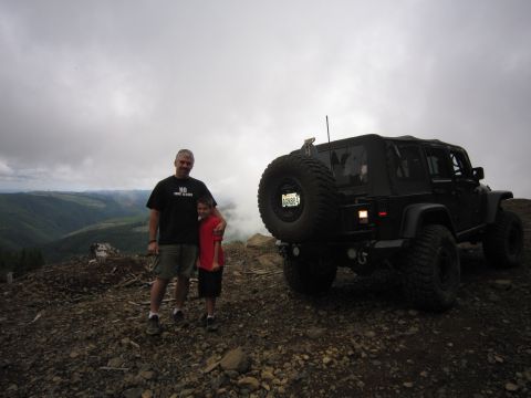 2008 Jeep Wrangler - Two people stand next to a black Jeep Wrangler on a mountain overlook under a cloudy sky.