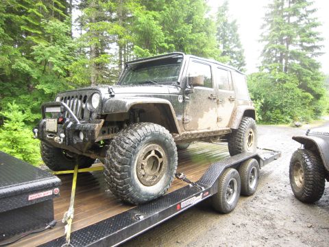 2008 Jeep Wrangler - A black Jeep Wrangler is loaded onto a trailer, with another Jeep partially visible on the right.