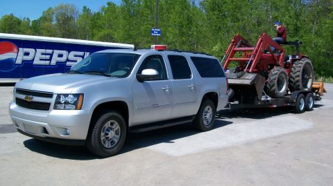 2000 Chevrolet Tahoe - A silver Chevrolet Suburban is seen towing a red tractor on a trailer.