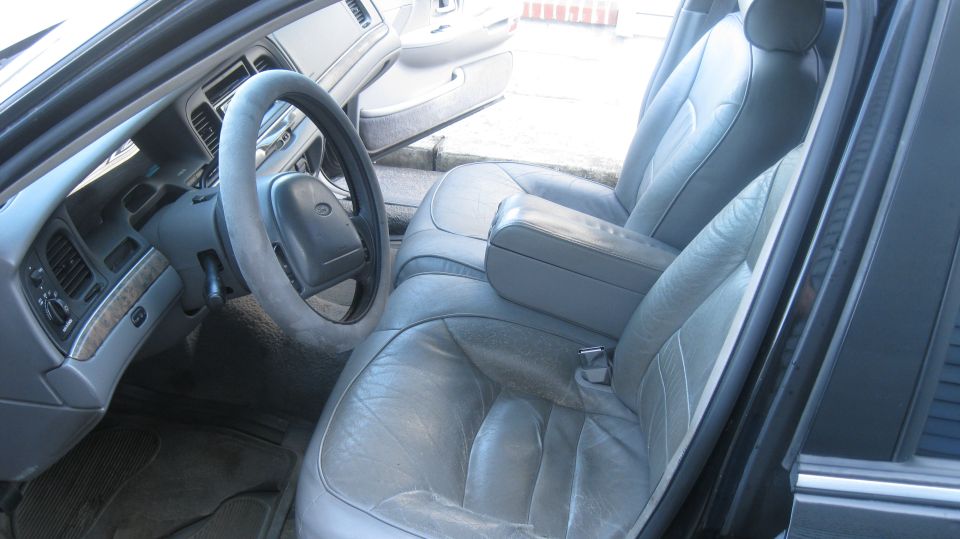 Gray leather interior of a 1999 Ford Crown Victoria, showing the steering wheel, dashboard, and front seats