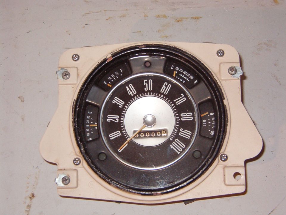 Vintage round speedometer instrument cluster removed and laid on a workbench